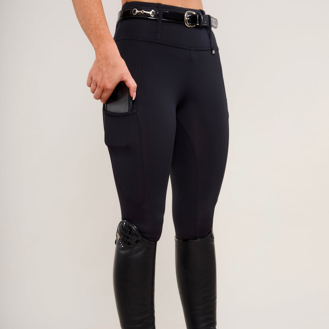 View demonstrating the use of phone pocket of HORZEHOODS® Black Luxe Equestrian Riding Leggings showcasing high-waist design