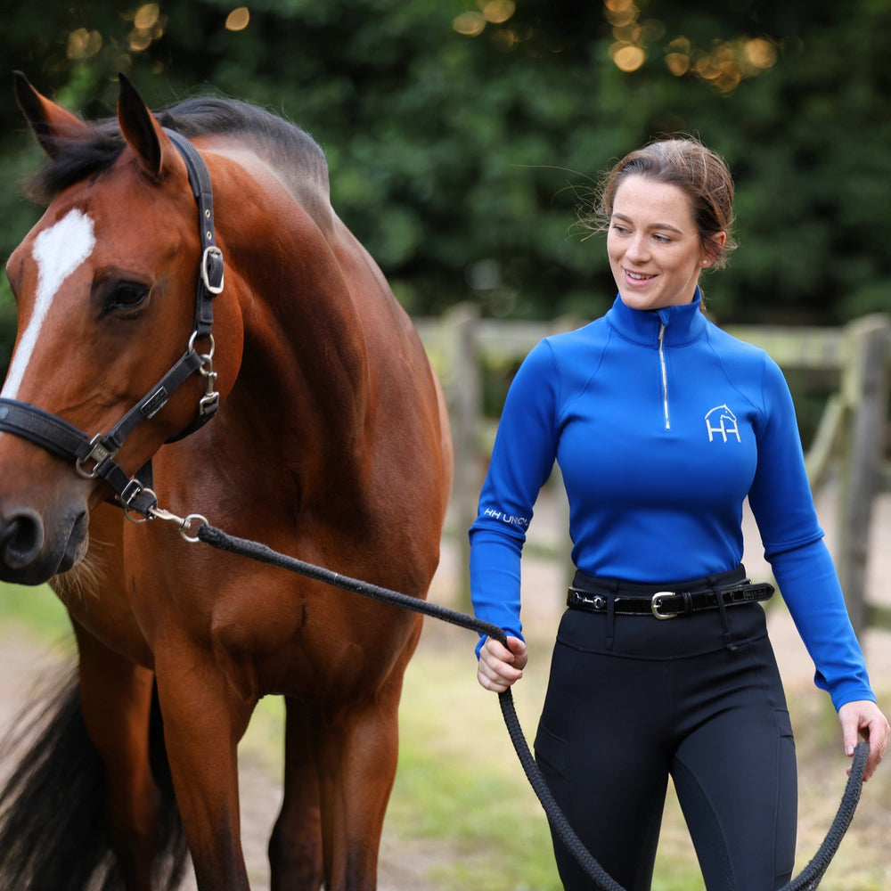 Front view image of horse and rider in blue thermal women’s equestrian base layer 