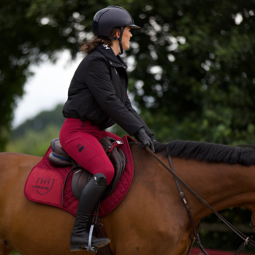 Burgundy Berry AirGel Pad in action with a rider in a brown jump saddle and wearing matching horse riding leggings